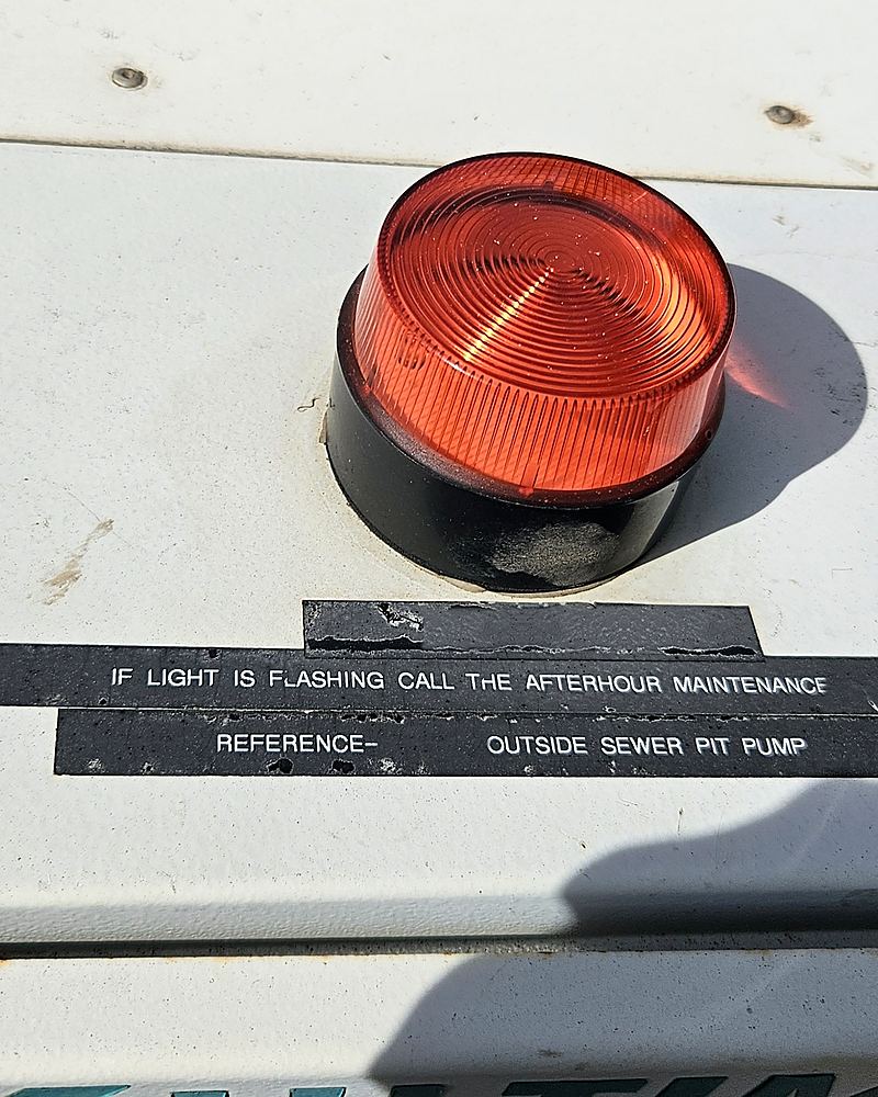 Engraved label on the panel lid reading: if light is flashing call the afterhour maintenance